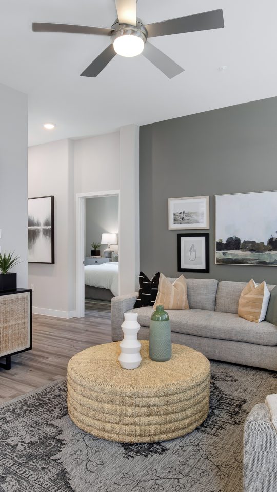 a living room with gray walls and a ceiling fan at The VLux Trails